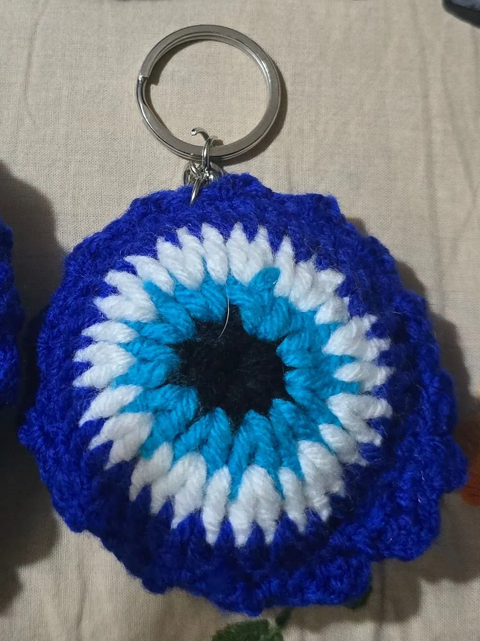 Crochet evil-eye keychain with a scalloped royal blue edge on a metal key ring
