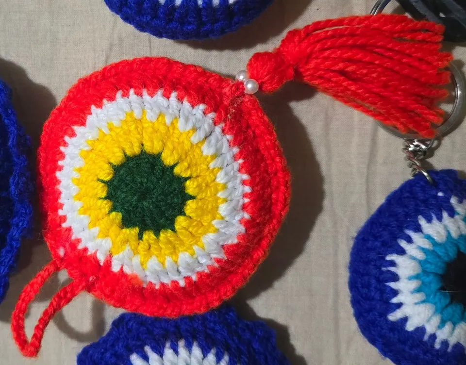 Red crochet evil-eye charm with its red tassel and pearl-style beads