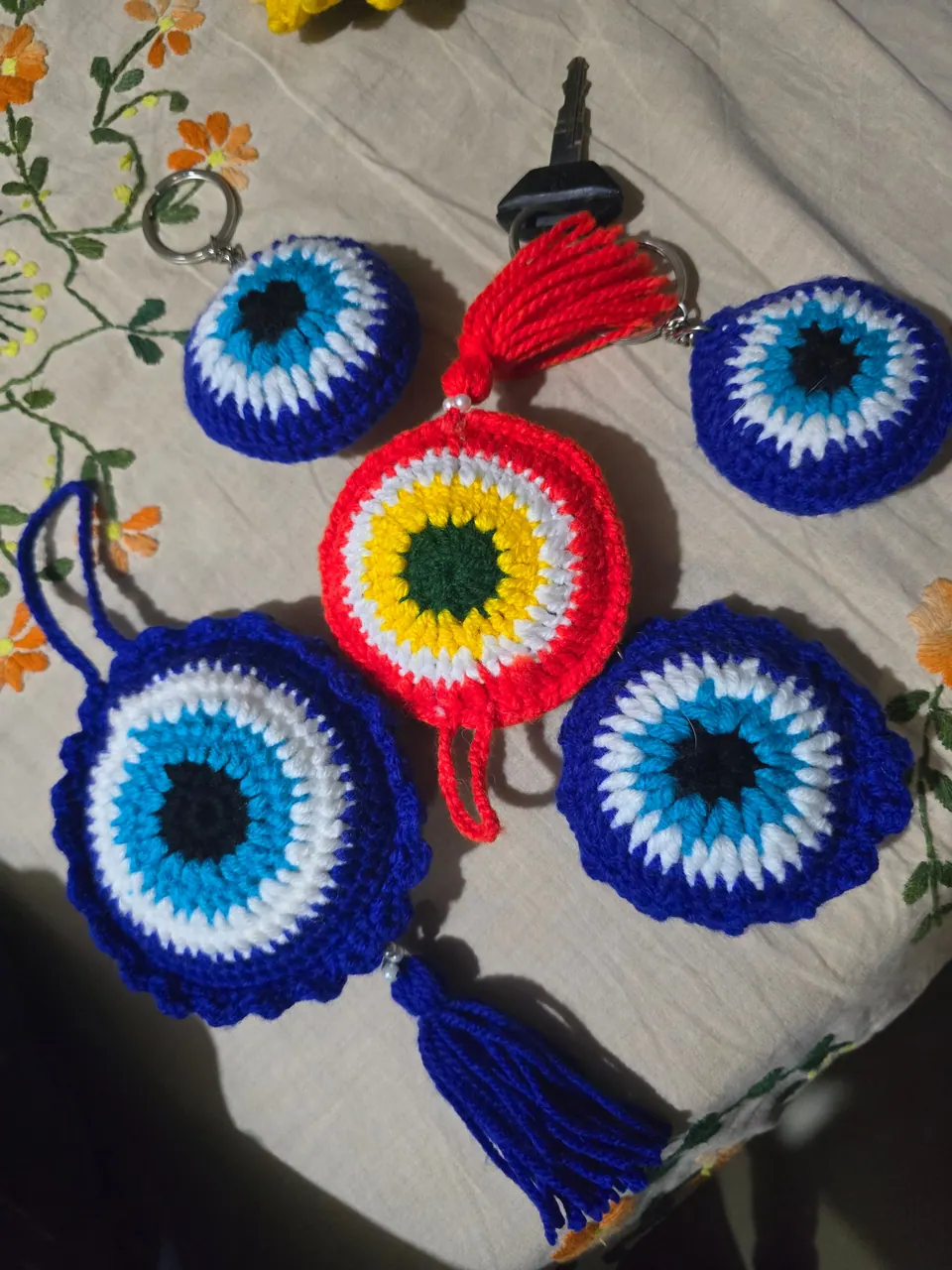 Red crochet evil-eye charm in the middle of blue crochet evil-eye keychains and a blue tassel charm