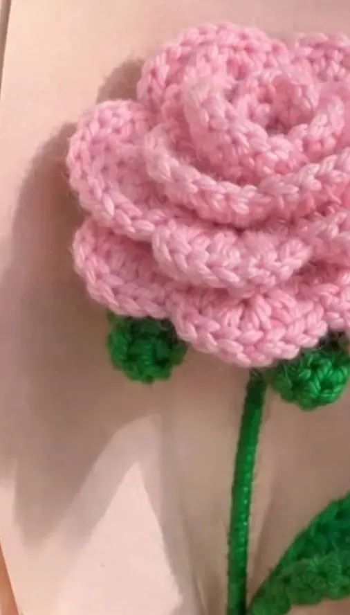 Close-up of the pink crochet rose petals and green crochet leaves